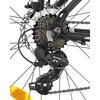 Zbliżenie na mechanizm przerzutki rowerowej z widocznymi zębatkami i łańcuchem. Na przerzutce widoczne są napisy "Tourney" i "Shimano", a na zębatkach "Shimano".