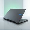 Na zdjęciu widoczny jest laptop z zamkniętą pokrywą, na której znajduje się logo "GIGABYTE" w niebieskim kolorze. Laptop stoi na białej, błyszczącej powierzchni, a w tle widać delikatne zielonkawe oświetlenie.