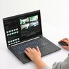 Na zdjęciu widoczny jest laptop z otwartym ekranem, na którym wyświetlane są różne obrazy i interfejs oprogramowania do generowania grafiki. Klawiatura laptopa jest podświetlona, a obok znajduje się ręka trzymająca myszkę.