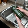 Zielony termos na jedzenie marki NILS CAMP o pojemności 1000 ml jest trzymany nad zlewem, a woda z kranu spływa po jego powierzchni. Na termosie widoczne jest logo "NILS" oraz symbole wskazujące na jego funkcje.