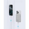 Na zdjęciu widoczny jest szary powerbank z napisem "AUKEY" oraz oznaczeniem "10000 mAh", podłączony do smartfona za pomocą kabla. Obok znajduje się smartfon z wyświetlonym ekranem, również podłączony do kabla, a na obu kablach widoczne są niebieskie strza