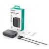 Na zdjęciu znajduje się szary powerbank z napisem "10000" oraz "AUKEY", obok którego leży czarny kabel USB i instrukcja obsługi. W tle widoczne jest opakowanie z napisem "AUKEY Spark Mini 10000 Compact Fast Charging Power Bank".