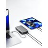 Na zdjęciu znajduje się szary powerbank z logo "AUKEY" podłączony do laptopa i tabletu, z wyświetlaczem pokazującym stan naładowania. Obok powerbanka widoczne są kable łączące urządzenia, a na ekranie tabletu wyświetlana jest godzina 16:38.