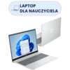 Na zdjęciu widoczny jest srebrny laptop z logo HP, z otwartym ekranem wyświetlającym interfejs systemu Windows 11. Nad laptopem znajduje się napis "LAPTOP DLA NAUCZYCIELA" na niebieskim tle z ikoną laptopa.