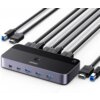 Na zdjęciu znajduje się przełącznik KVM marki UGREEN z kilkoma podłączonymi kablami HDMI i USB, na którym widoczne są porty oznaczone jako "CONTROL", "5Gbps" oraz logo "UGREEN". Produkt ma elegancki, ciemny design z zaokrąglonymi krawędziami i przyciskiem