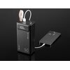 Czarny powerbank z wyświetlaczem pokazującym "100%" oraz oznaczeniami "Tracer", "50+", "Quick Charge 3.0" i "PD", z podłączonymi dwoma kablami USB, z których jeden łączy się z czarnym smartfonem. Powerbank ma skórzany uchwyt i leży na czarnym tle.
