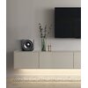 Na zdjęciu znajduje się nowoczesny salon z wiszącą szafką, na której stoi subwoofer oraz wazon z gałązkami i świeczniki. Na ścianie wisi duży telewizor, a pod szafką znajduje się podświetlany dywanik.