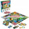 Pudełko gry planszowej "Monopoly Pokémon" z kolorową grafiką przedstawiającą postacie Pokémon oraz rozłożona plansza z różnorodnymi polami i kartami. Widoczne są również pionki, żetony w kształcie Pokéballi oraz kości do gry.