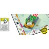 Na zdjęciu znajduje się plansza do gry Monopoly z dodatkiem "Wykup wszystko", na której widoczny jest element z kartami i kostką. Po lewej stronie znajduje się karta z napisem: "BANK - To zdolność jest aktywna, dopóki masz tę kartę. Jesteś właścicielem Ba