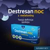 Opakowanie suplementu diety "Destresan noc z melatoniną" marki OLEOFARM, zawierające 30 kapsułek, jest przedstawione na tle nocnego nieba z chmurami i księżycem. Na opakowaniu widnieje tekst: "suplement diety", "Destresan noc z melatoniną", "Twoja definic