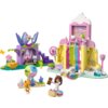 Zestaw LEGO przedstawia kolorową scenę z elementami przypominającymi domek dla lalek, w tym różowe i żółte budynki, zjeżdżalnię oraz figurki zwierząt i postaci. Na zdjęciu widoczne są także dekoracje w kształcie lizaków i babeczek oraz różnorodne akcesoria, takie jak kryształy i rośliny.