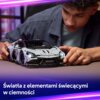 Na zdjęciu widoczny jest model samochodu LEGO 42214 Technic Supersamochód Lamborghini Revuelto, który jest trzymany przez osobę. Na dole zdjęcia znajduje się napis: "Światła z elementami świecącymi w ciemności".