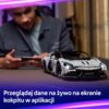 Na zdjęciu znajduje się model samochodu z klocków LEGO, a w tle osoba trzymająca urządzenie mobilne. Na dole widoczny jest tekst: "Przeglądaj dane na żywo na ekranie kokpitu w aplikacji".