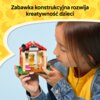 Na zdjęciu widoczny jest zestaw LEGO przedstawiający mały domek z czerwonym dachem i figurką wewnątrz, trzymany przez dziecko. W górnej części zdjęcia znajduje się tekst: "Zabawka konstrukcyjna rozwija kreatywność dzieci".
