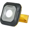 Na zdjęciu znajduje się reflektor o czarno-szarej obudowie z widocznym logo "STANLEY" na górze. Reflektor ma żółty uchwyt z boku.