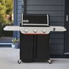 Grill gazowy z trzema pokrętłami na panelu przednim, z widocznym logo "Weber" oraz napisem "Genesis" na obudowie. Grill stoi na tarasie przed ciemną elewacją budynku, obok rośliny w doniczce.