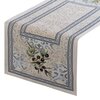 Bieżnik o wymiarach 40 x 100 cm w kolorze naturalnym, ozdobiony wzorem z gałązkami oliwnymi i geometrycznymi motywami w odcieniach niebieskiego i szarości. Brzegi bieżnika zdobią dekoracyjne obramowania.