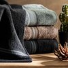 Ciemnobeżowy ręcznik o wymiarach 70 x 140 cm z widoczną teksturą frotte. W centralnej części znajduje się ozdobny pas z poziomymi, falistymi liniami w różnych odcieniach beżu i brązu.