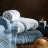Zdjęcie przedstawia niebieski ręcznik o wymiarach 50 x 90 cm z widocznym pasem dekoracyjnym w odcieniach brązu, bieli i szarości. Struktura materiału jest puszysta i miękka, co sugeruje wysoką chłonność.