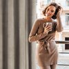 Zasłona w kolorze brązowym o fakturze przypominającej welur, zawieszona w pomieszczeniu z widokiem na balkon. W tle widoczne są elementy architektury budynku.