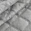 Srebrna narzuta o wymiarach 200 x 220 cm z widocznym wzorem w romby, wykonana z materiału o połyskującej fakturze. Produkt ma delikatne przeszycia wzdłuż krawędzi rombów.