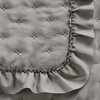 Beżowa narzuta z widocznym pikowaniem w kształcie małych gwiazdek oraz ozdobną falbaną na krawędzi. Materiał ma delikatną fakturę, która dodaje elegancji.