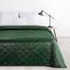 Zielona narzuta o wymiarach 170 x 210 cm z widocznym wzorem w romby, rozłożona na łóżku z białymi poduszkami. Obok łóżka znajduje się drewniany stolik z czarną lampką.