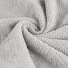 Srebrny ręcznik o fakturze frotte, ułożony w miękkie fałdy, z widocznym wzorem wzdłuż krawędzi. Produkt to "Ręcznik Loren (02) 70 x 140 cm Srebrny".