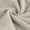 Jasnobeżowy ręcznik o wymiarach 30 x 50 cm, z widoczną fakturą frotte, ułożony w miękkie fałdy. Na powierzchni ręcznika widać delikatny wzór geometryczny.