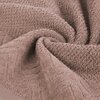 Zdjęcie przedstawia zbliżenie na miękki, pudrowy ręcznik o fakturze frotte, z widocznym wzorem geometrycznym. Materiał jest lekko pofałdowany, co podkreśla jego puszystość i strukturę.