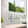 Biała firana o wymiarach 150 x 30 cm wisi na oknie, ozdobiona jest kolorowymi kwiatowymi wzorami oraz koronkowym wykończeniem na dole. W okrągłym zbliżeniu widoczny jest szczegółowy wzór koronki i tkaniny.