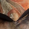 Zbliżenie na pościel z abstrakcyjnym wzorem w odcieniach kremowym, brązowym i pomarańczowym, z widocznymi liniami i kształtami geometrycznymi. Materiał ma delikatny połysk i gładką teksturę.