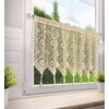 Jasnobeżowa firana o wymiarach 150 x 60 cm z delikatnym, ażurowym wzorem wisi na oknie, przez które widać rozmyty krajobraz z zielenią. Na parapecie znajdują się dwie doniczki z zielonymi roślinami.