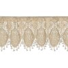 Beżowa firana o wymiarach 150 x 30 cm z ozdobnym, ażurowym wzorem w kształcie owalnych motywów. Na dolnej krawędzi znajdują się frędzle, które dodają elegancji całości.