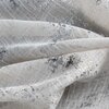 Zbliżenie na materiał zasłony o teksturze siatki w kolorze naturalno-srebrnym z nieregularnymi, srebrnymi wzorami. Tkanina jest lekko pofałdowana, co podkreśla jej strukturę i połysk.