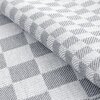 Zdjęcie przedstawia zbliżenie na materiał o wzorze w szaro-białą kratkę, z wyraźnie widoczną fakturą tkaniny. Produkt to ściereczka EUROFIRANY Mauro o wymiarach 50 x 70 cm w kolorze srebrnym, dostępna w zestawie dwóch sztuk.