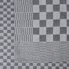 Zdjęcie przedstawia fragment materiału o różnorodnych wzorach geometrycznych, takich jak szachownica, paski i krzyżujące się linie. Tkanina ma odcienie szarości, tworząc kontrastowe wzory na całej powierzchni.