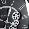 Zbliżenie na tarczę zegara ściennego z widocznymi rzymskimi cyframi, wskazówkami oraz ozdobnymi zębatkami. Na tarczy znajduje się tekst: "Westminster Clock Company London".