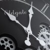 Zbliżenie na tarczę zegara ściennego z widocznymi białymi wskazówkami i mechanizmem zębatkowym w tle. Na tarczy znajduje się napis "Oldgate".