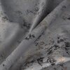 Zdjęcie przedstawia fragment zasłony o srebrnym kolorze z nieregularnym wzorem w odcieniach czerni i brązu. Materiał jest lekko pofałdowany, co dodaje mu tekstury i głębi.