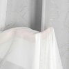 Biała firana o delikatnym, subtelnym wzorze z lekkim połyskiem, zawieszona na tle o podobnym wzorze. Materiał jest lekki i półprzezroczysty, co nadaje mu elegancki wygląd.