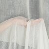Przezroczysta, kremowa zasłona o delikatnej fakturze, układająca się w miękkie fałdy. Tkanina jest lekka i przepuszcza światło, tworząc subtelny efekt wizualny.