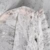 Zdjęcie przedstawia fragment białej firany z kolekcji EUROFIRANY Olivia o wymiarach 140 x 250 cm. Materiał ma delikatny, srebrzysty wzór, który dodaje mu elegancji i subtelnego połysku.