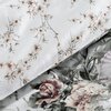 Zdjęcie przedstawia fragment pościeli z wzorem roślinnym, na którym widoczne są liście i kwiaty w odcieniach zieleni, różu i beżu na białym tle. Wzór jest gęsty i szczegółowy, tworząc elegancki i naturalny wygląd.