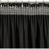 Czarno-szampańska zasłona o wymiarach 140 x 270 cm, zawieszona na metalowym karniszu za pomocą metalowych kółek i klipsów. Górna część zasłony ma przezroczysty pas z poziomymi liniami.
