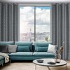 Na zdjęciu znajduje się salon z dużym oknem, przez które widać panoramę miasta. W pomieszczeniu znajduje się turkusowa sofa z poduszkami, okrągły stolik z wazonem i zasłony w stalowo-srebrnym kolorze z geometrycznym wzorem.