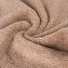 Zbliżenie na teksturę miękkiego, puszystego ręcznika w pudrowym kolorze, układającego się w spiralny wzór. Materiał ma gęsty splot, co podkreśla jego grubość i jakość.