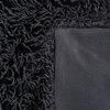 Zdjęcie przedstawia fragment czarnego koca z wyraźnie widoczną różnicą w fakturze materiału. Po jednej stronie znajduje się gładka powierzchnia, a po drugiej stronie widoczna jest puszysta, włochata struktura.