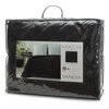 Przezroczyste opakowanie zawiera czarną narzutę z pikowanym wzorem, a na etykiecie widnieje napis: "NARZUTA VANESA" oraz rozmiar "170 x 210 cm". W tle etykiety znajduje się zdjęcie łóżka z narzutą, a obok widoczna jest roślina w doniczce.
