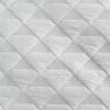 Zdjęcie przedstawia srebrną narzutę z geometrycznym wzorem w formie rombów, z perforowanymi detalami w niektórych częściach. Materiał ma delikatną fakturę i jednolity kolor.